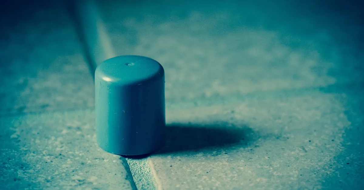 rubber floor-mounted door stopper cap sitting on a tiled floor at a doorway