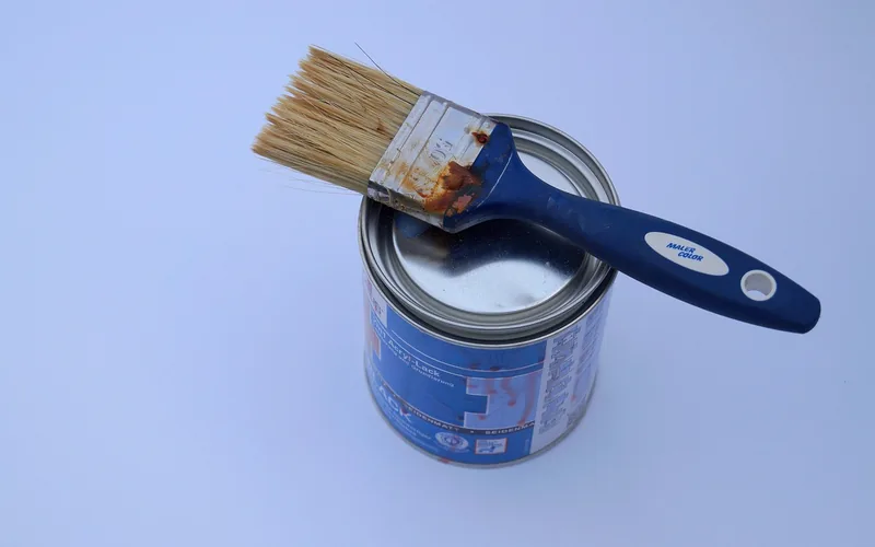 paintbrush resting on an open paint can used for porcelain refinishing
