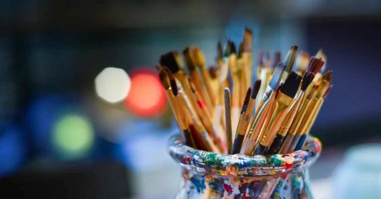 jar of clean paintbrushes with different bristle shapes stored upright in an art studio