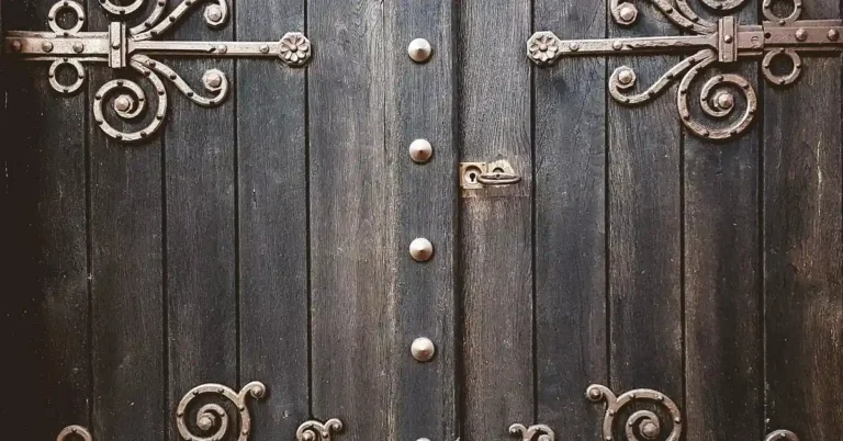 Heavy-duty wrought iron hinge mounted on a thick wooden gate door