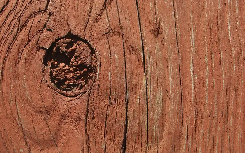 reddish stain soaking into a wood deck board around a knot