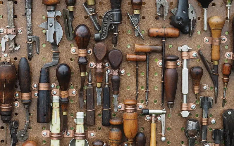wall of wood-handled hand tools with metal heads hanging in a workshop