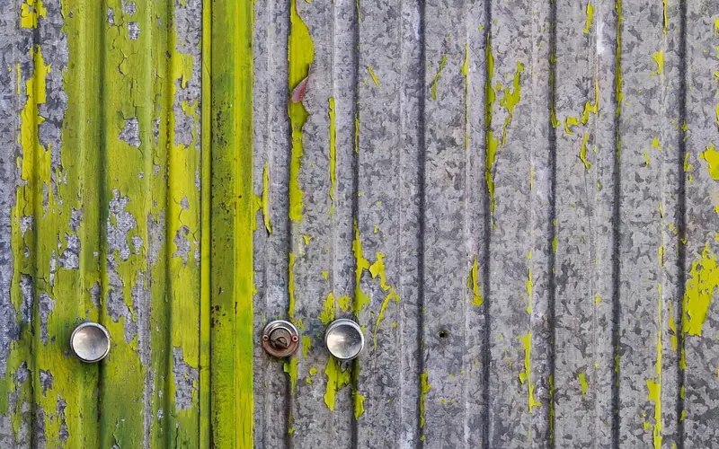peeling green paint on a metal door revealing bare metal underneath