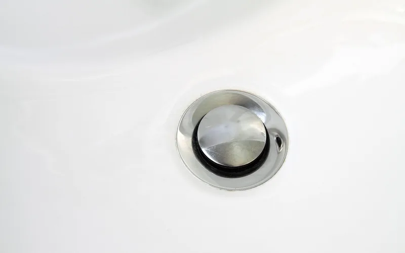 close-up of a chrome bathroom sink drain stopper where hair typically collects