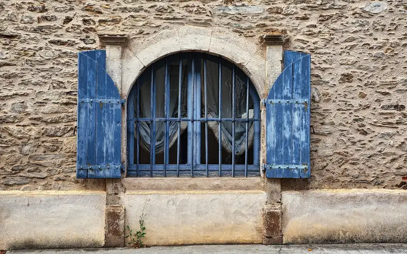 blue shutters with visible hinges mounted on a stone wall