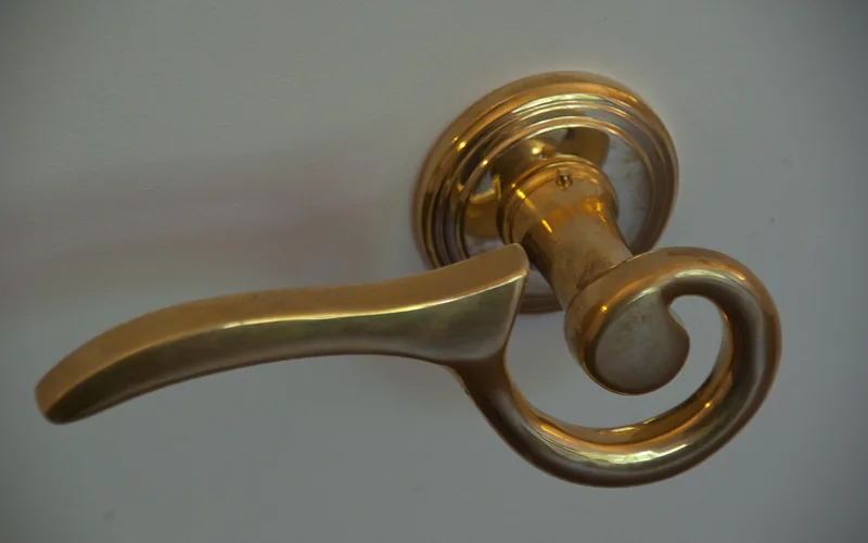 Brass lever door handle mounted on rose showing screw access point
