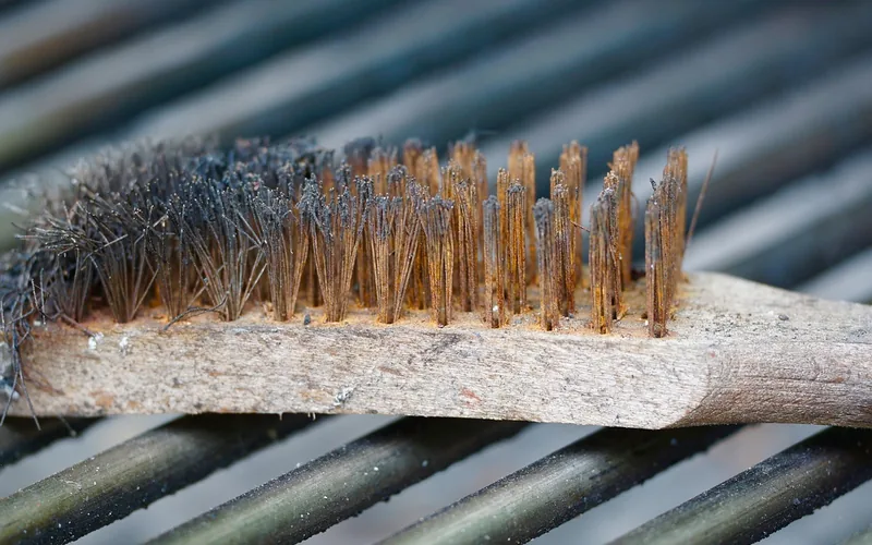 Wire brush removing rust and grime from a metal hinge pin