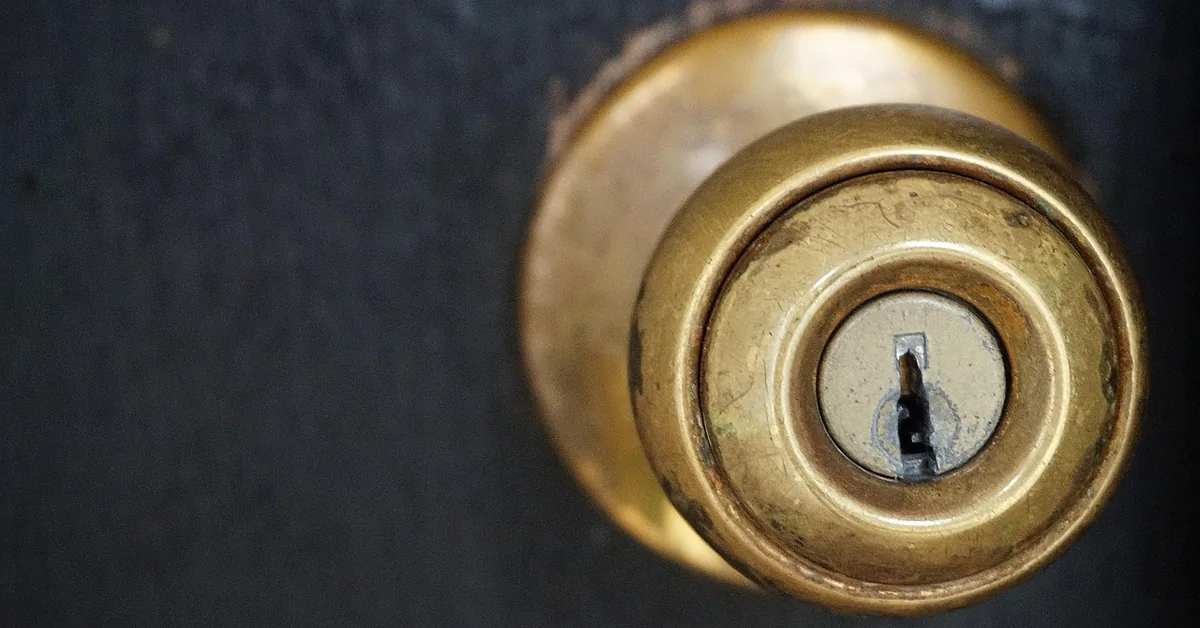 Brass keyed door knob lock cylinder with key inserted, close-up