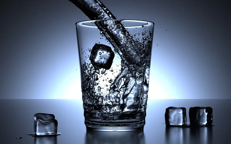 clear glass of water being poured with ice cubes, representing morning hydration