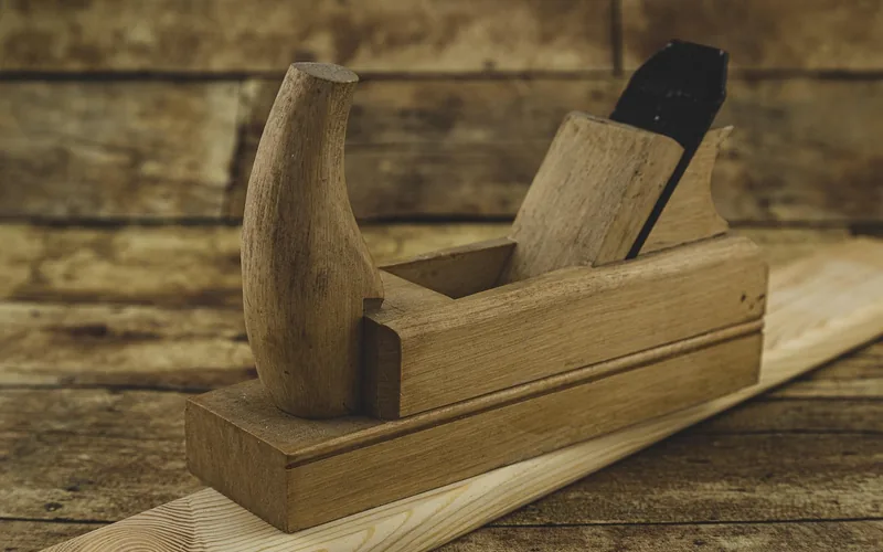 wood hand plane resting on a freshly trimmed pine board edge