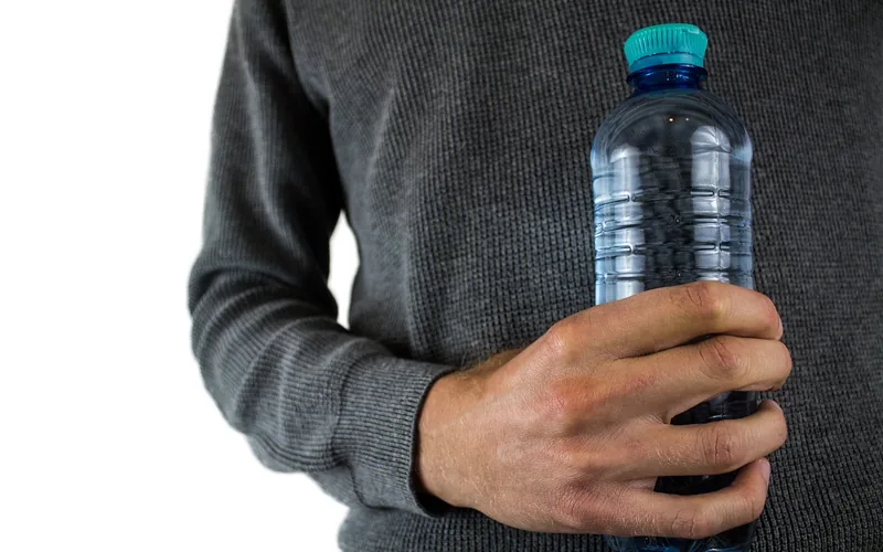 person holding a plastic water bottle to stay hydrated during the day