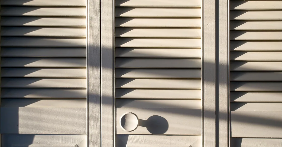louvered bifold closet doors with pull holes, afternoon sunlight casting shadow lines