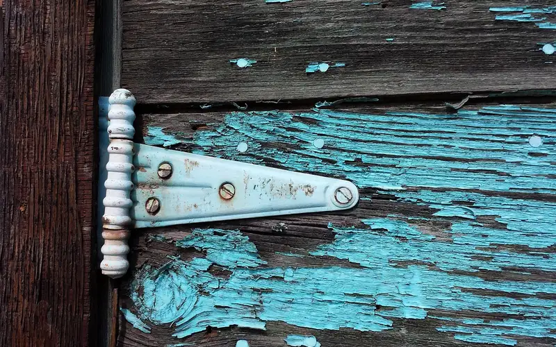 Old door hinge with peeling paint before removal Old door hinge with peeling paint before removal