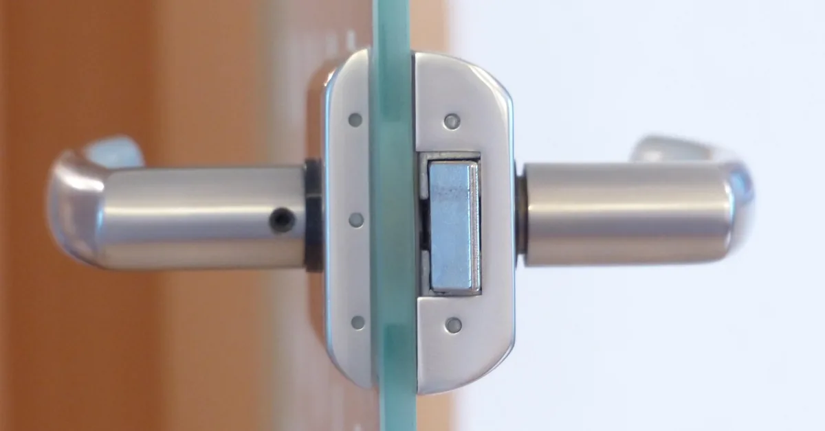 close-up of a lock mechanism mounted through a glass sliding door panel