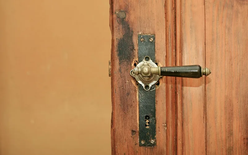 antique iron latch and lock mechanism mounted on an old wooden door