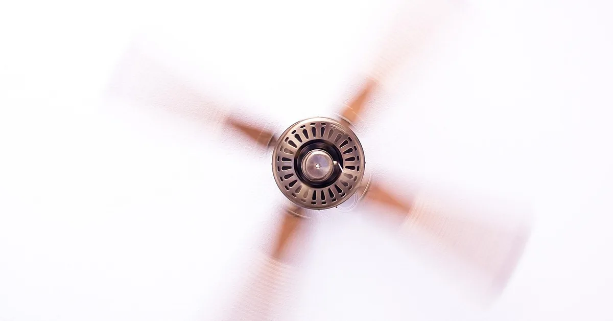 Ceiling fan spinning with visible pull chain switch housing below the blades