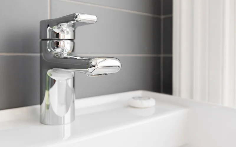 Modern brushed nickel style faucet next to a bar of soap on a clean bathroom counter Modern brushed nickel style faucet next to a bar of soap on a clean bathroom counter