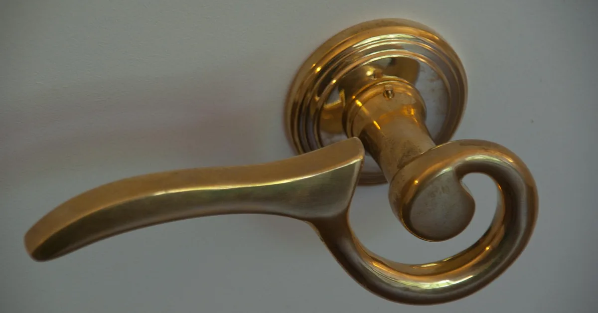 brass lever door handle installed on a white painted door