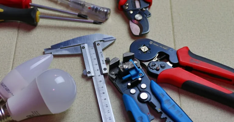 Electrician's tools, wire strippers, calipers, and LED bulbs laid out for a recessed lighting instal