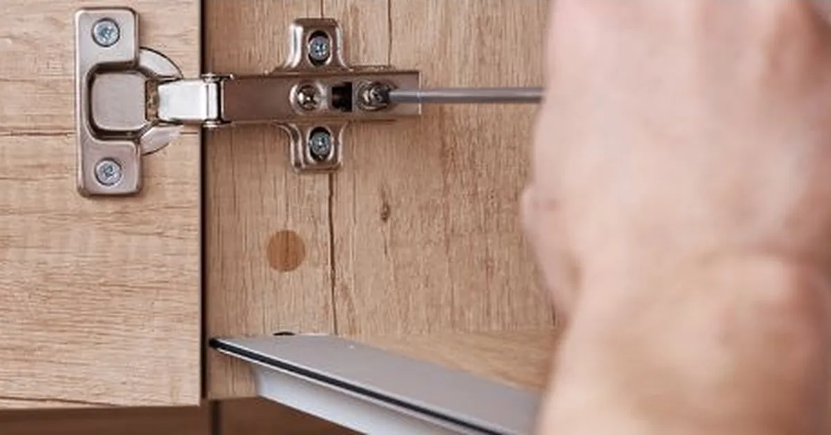 Hand using a screwdriver to adjust a hinge mechanism, similar to seating a hinge pin door stop
