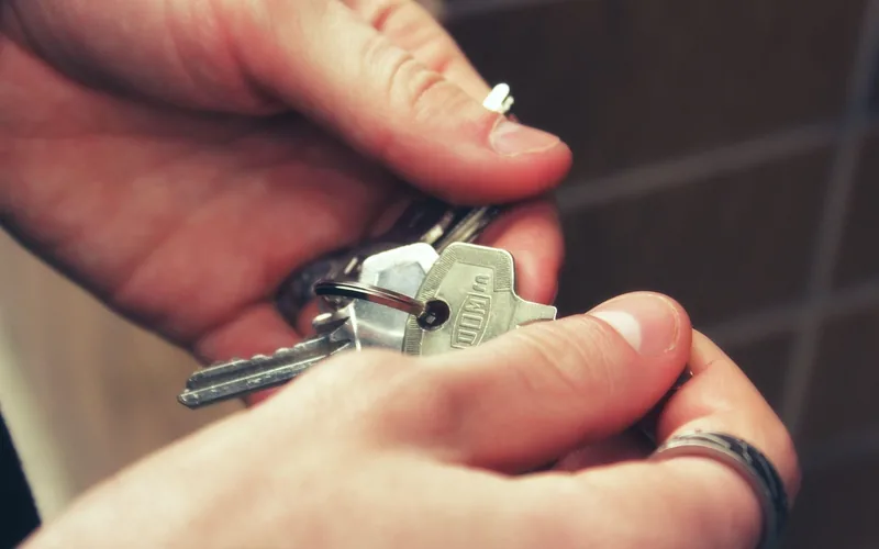 two hands holding a set of house keys before a Kwikset SmartKey reset