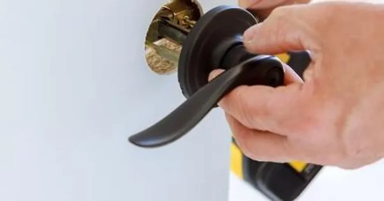 Hand tightening a lever door handle onto the spindle during assembly