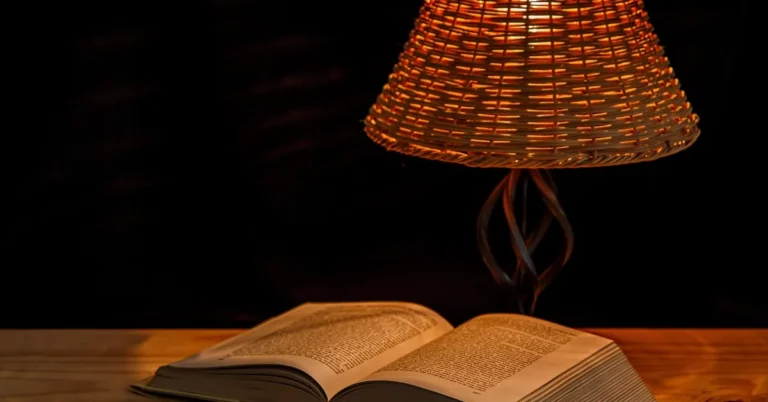woven wicker lampshade glowing warmly on a bedside table lamp next to an open book