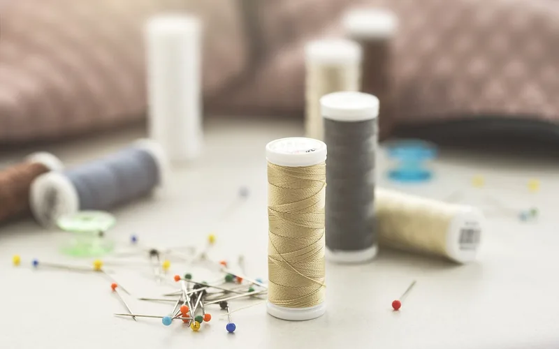 sewing thread spools, pins, and craft supplies laid out for lampshade fabric repair sewing thread spools, pins, and craft supplies laid out for lampshade fabric repair