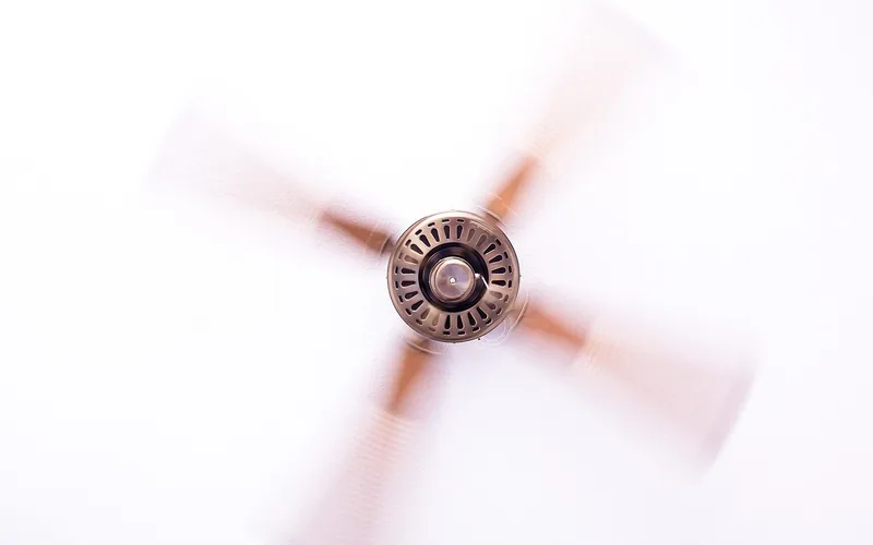 modern ceiling fan spinning on a white ceiling, low-amp DC motor style