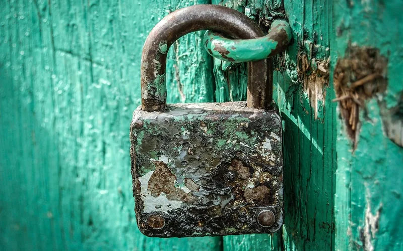 An old rusty padlock mounted on a weathered door An old rusty padlock mounted on a weathered door