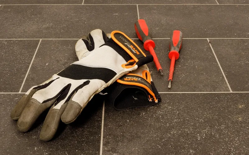 protective work gloves and screwdrivers laid out before a door repair job protective work gloves and screwdrivers laid out before a door repair job