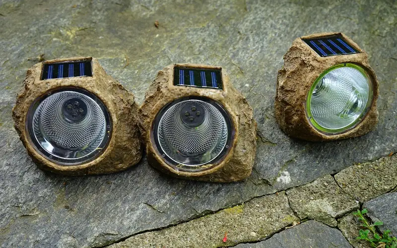 three decorative solar-powered garden lights showing their small built-in solar panels three decorative solar-powered garden lights showing their small built-in solar panels