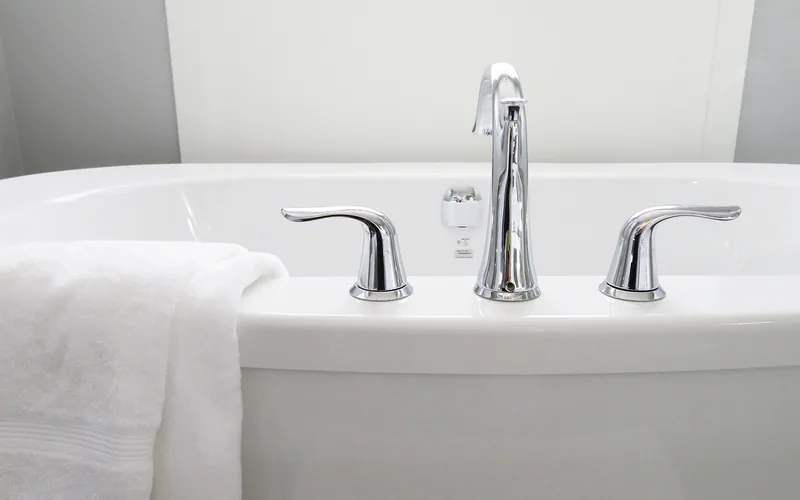 Close-up of a bathtub faucet and rim on a white porcelain tub