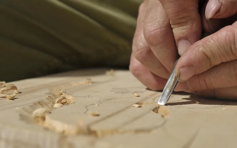 Carpenter using a chisel to carve wood