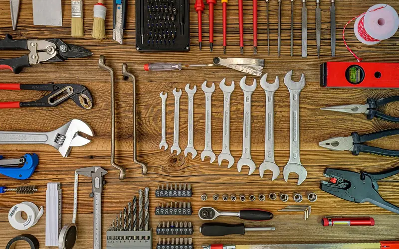 Hand tools including screwdriver, wrench, and level laid out for a repair job