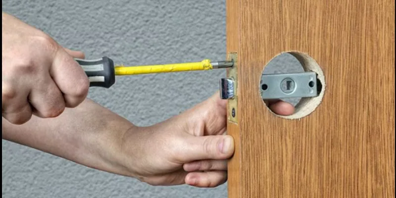 Installing a latch and strike plate into the door edge with a screwdriver after measuring the latch bore
