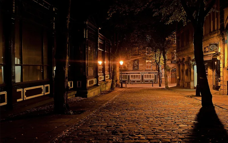 an old cobblestone street lit by a warm orange lamp at night