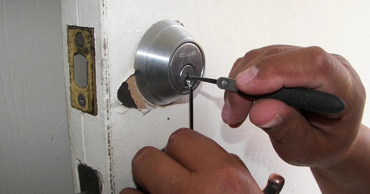 hands using a tension tool to remove a residential door latch and deadbolt mechanism