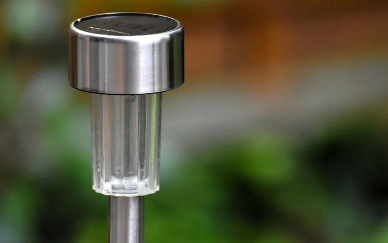 close-up of a solar garden light's panel and lens standing outdoors in sunlight