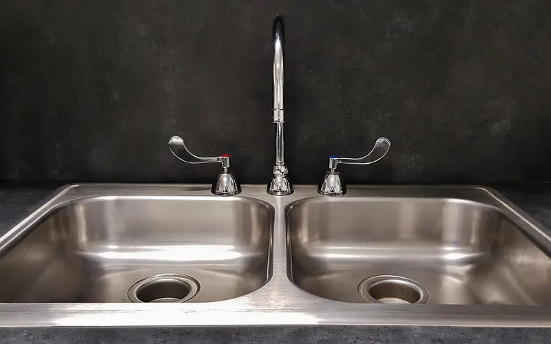 Stainless steel double-bowl kitchen sink with faucet installed in countertop Stainless steel double-bowl kitchen sink with faucet installed in countertop