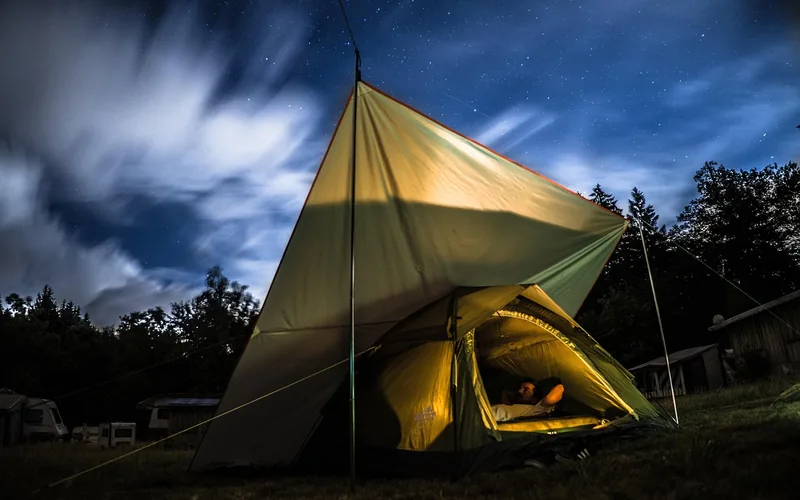 tarp pitched as an A-frame roof over a tent at night under a starry sky