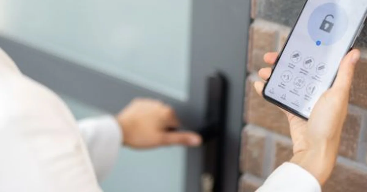 Hand holding a phone with the lock app open next to a Teeho smart door lock