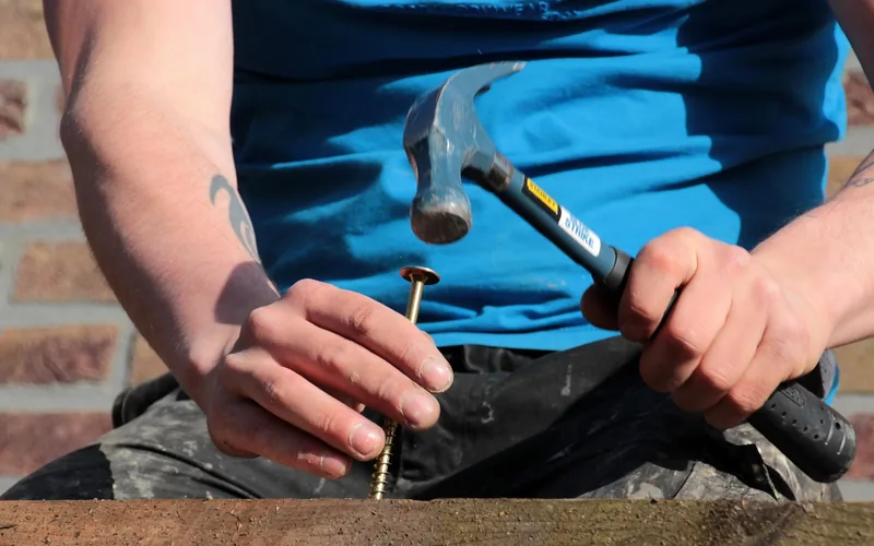 Fastener installation in pressure-treated lumber driving a corrosion-resistant fastener into a pressure-treated lumber board outdoors