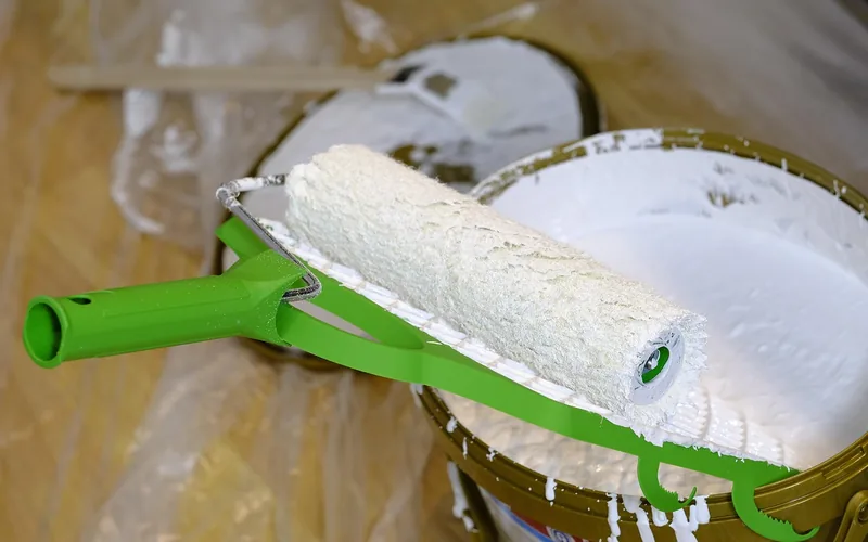 paint roller loaded with white primer next to an open can paint roller loaded with white primer next to an open can