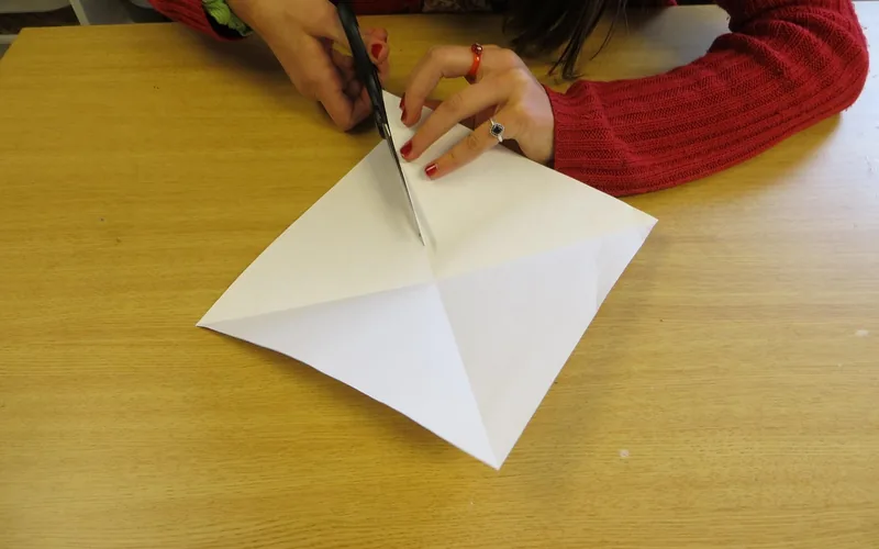 Hands cutting a folded paper panel to size for a lampshade frame Hands cutting a folded paper panel to size for a lampshade frame