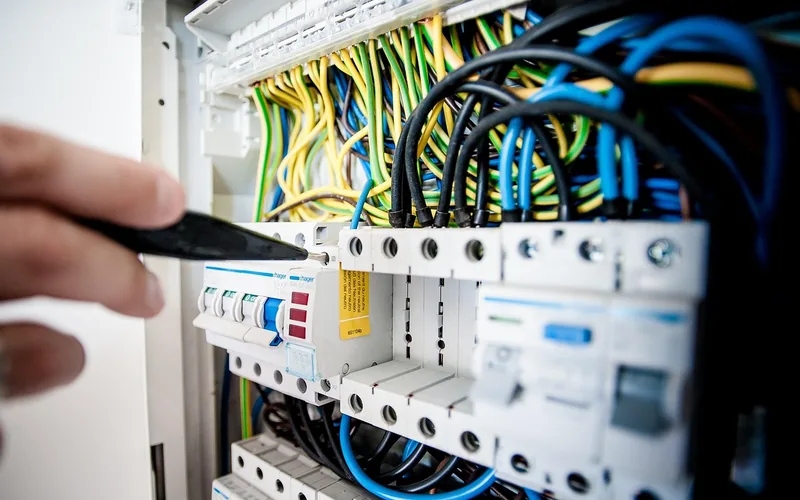 Hand switching off a circuit breaker before working on a light fixture junction box