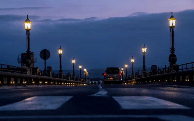 illuminated decorative lamp post along a paved road at dusk illuminated decorative lamp post along a paved road at dusk