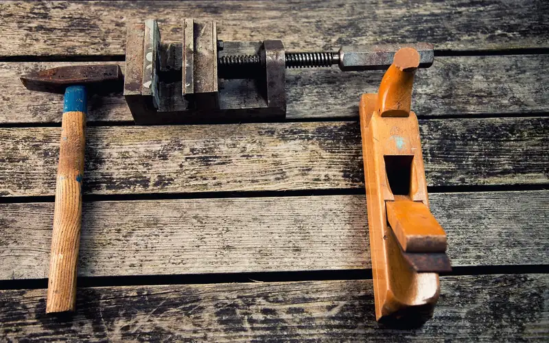 hammer, clamp, and hand plane laid out on a wood workbench before a door installation