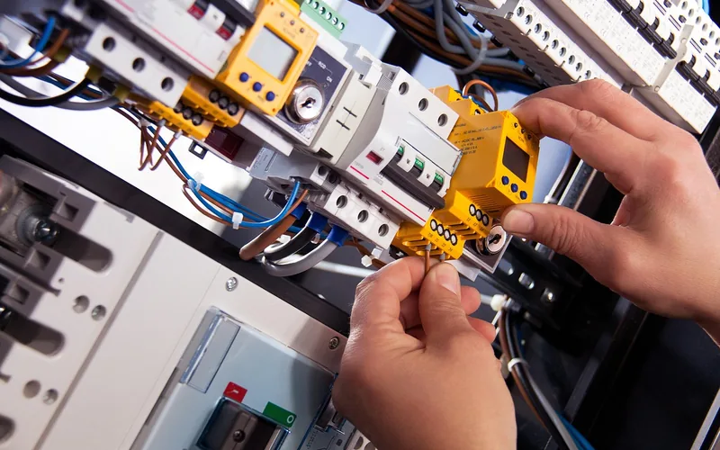 electrician hands connecting wiring at a breaker panel during a ballast bypass installation