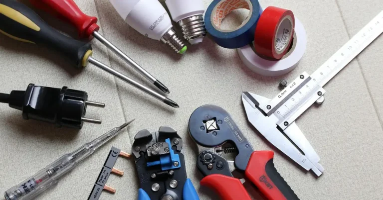 electrician using screwdriver near LED bulb, wire strippers, tape, and calipers laid out on a workbench